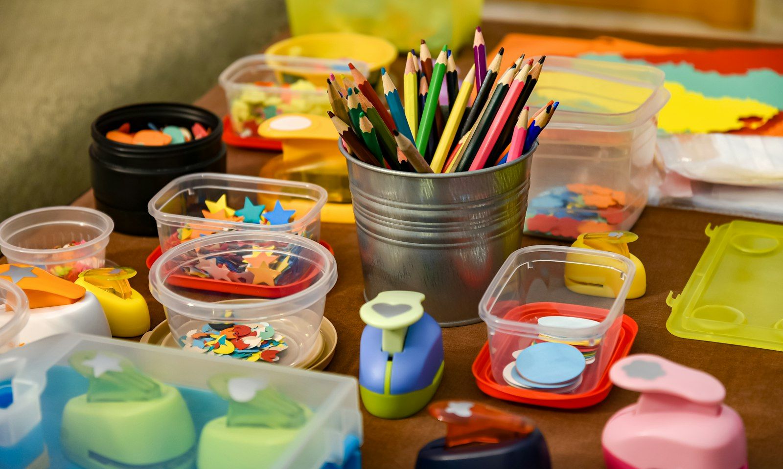Coloured pencils in a tin among tubs of craft supplies on a counter